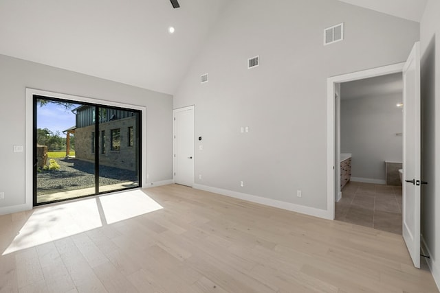 unfurnished room featuring light wood-type flooring and high vaulted ceiling