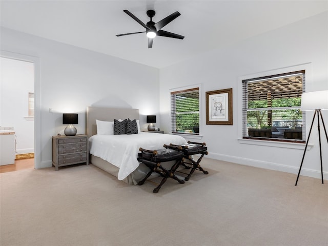 carpeted bedroom featuring multiple windows, ceiling fan, and ensuite bathroom