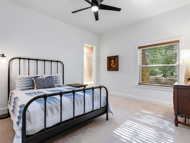 bedroom with ceiling fan, light colored carpet, and ensuite bath