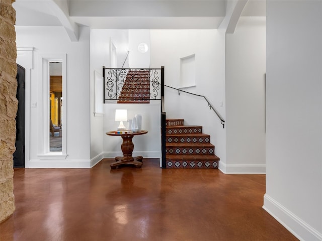 stairway with beam ceiling and concrete floors