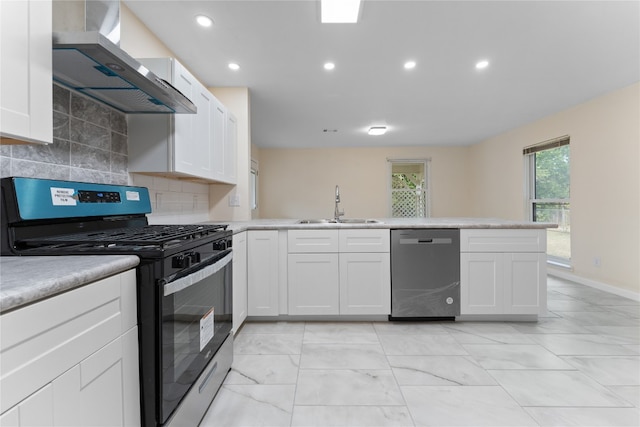 kitchen featuring wall chimney range hood, tasteful backsplash, white cabinetry, sink, and stainless steel appliances