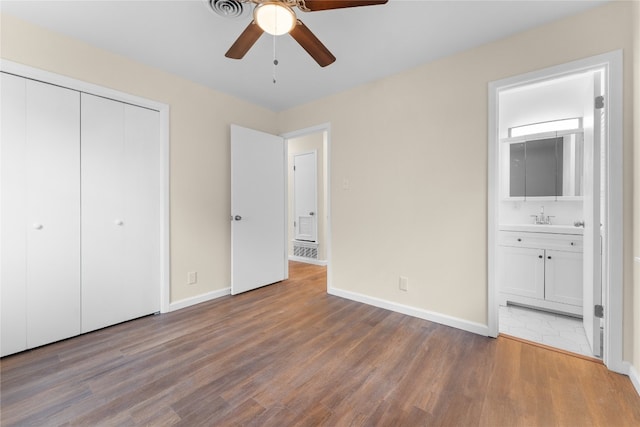 unfurnished bedroom featuring sink, ensuite bath, hardwood / wood-style floors, a closet, and ceiling fan