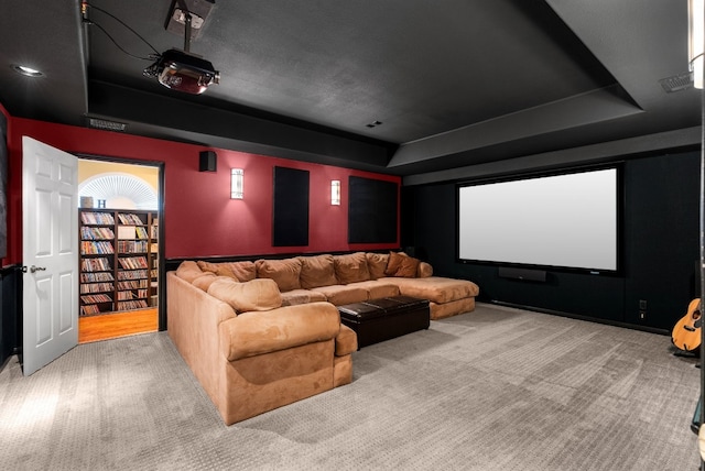 cinema featuring a raised ceiling and carpet