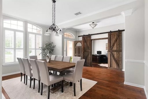 dining area with a notable chandelier, dark hardwood / wood-style floors, and a barn door