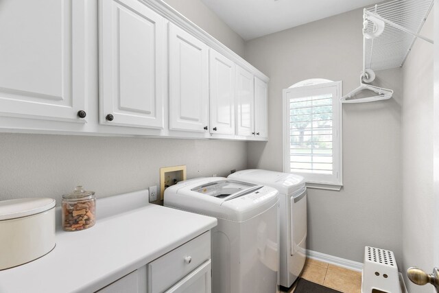 laundry area featuring cabinets, washer and dryer, and light tile patterned floors