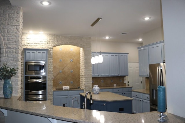 kitchen featuring hanging light fixtures, stainless steel appliances, tasteful backsplash, light stone countertops, and kitchen peninsula