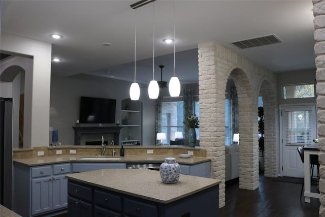 kitchen featuring hanging light fixtures, a kitchen island, sink, and dark wood-type flooring