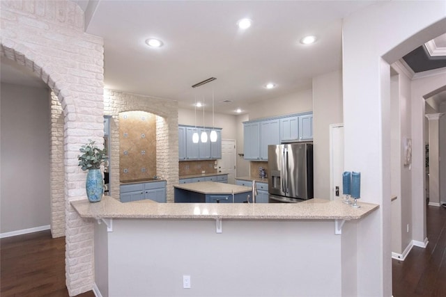 kitchen featuring stainless steel refrigerator with ice dispenser, dark wood-type flooring, a center island, kitchen peninsula, and pendant lighting