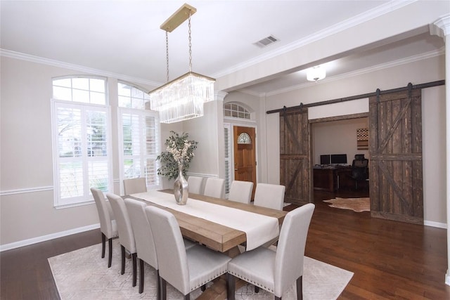 dining space with dark hardwood / wood-style floors, ornamental molding, a barn door, and a chandelier