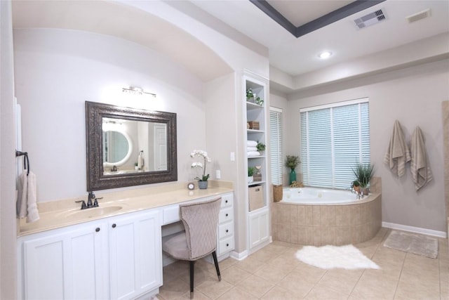 bathroom featuring a relaxing tiled tub, vanity, tile patterned flooring, and built in shelves