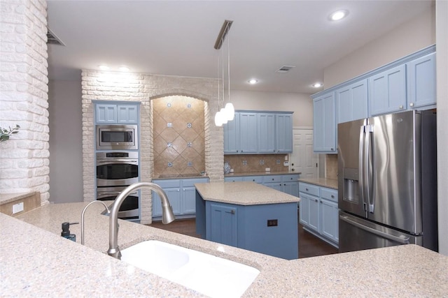 kitchen featuring pendant lighting, sink, appliances with stainless steel finishes, tasteful backsplash, and a kitchen island