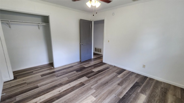 unfurnished bedroom featuring ceiling fan, a closet, crown molding, and dark wood-type flooring