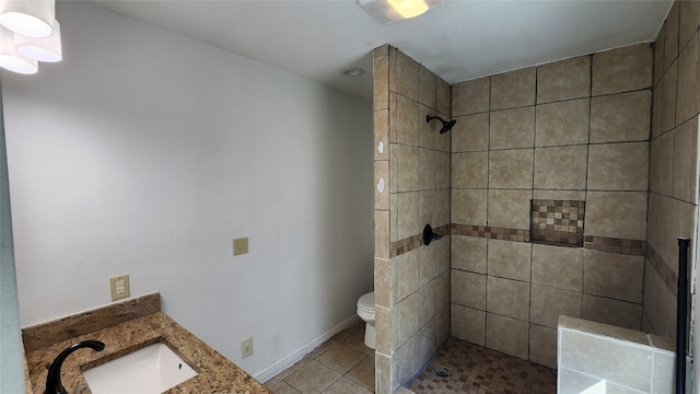 bathroom featuring vanity, tile patterned floors, toilet, and tiled shower