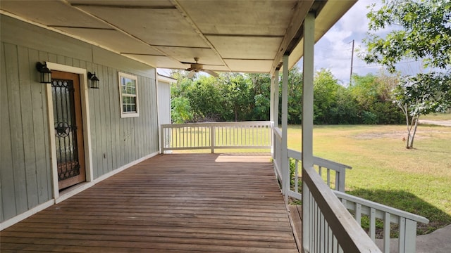 wooden terrace featuring ceiling fan and a yard