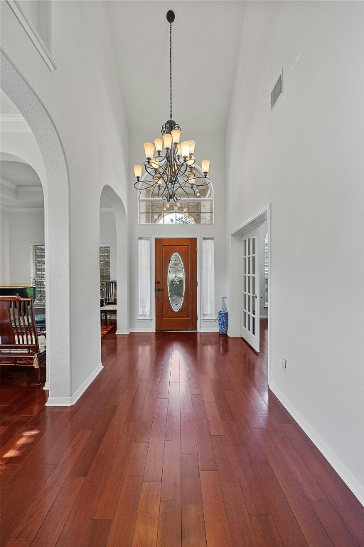 entryway with a high ceiling, dark hardwood / wood-style flooring, and a notable chandelier