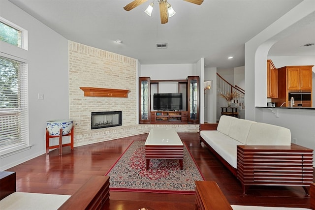 living room featuring ceiling fan, a fireplace, and dark hardwood / wood-style floors