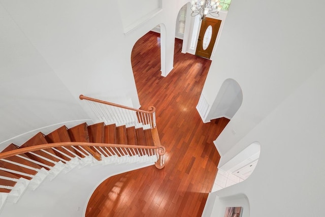 9228 Limoncillo Dr, Austin, TX 78750 - stairs with arched walkways, hardwood / wood-style floors, a towering ceiling, and a chandelier