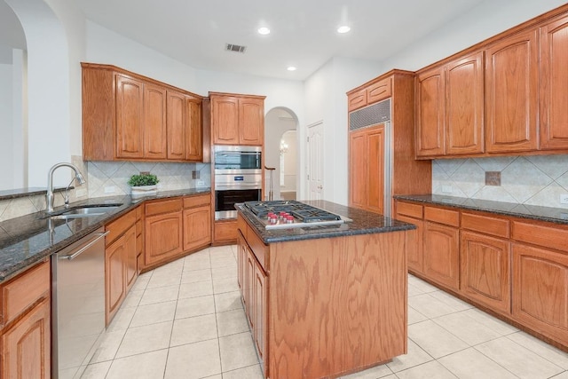 9228 Limoncillo Dr, Austin, TX 78750 - kitchen with arched walkways, appliances with stainless steel finishes, dark stone countertops, a kitchen island, and recessed lighting