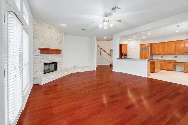 9228 Limoncillo Dr, Austin, TX 78750 - unfurnished living room featuring ceiling fan, light wood-style flooring, a brick fireplace, stairway, and recessed lighting