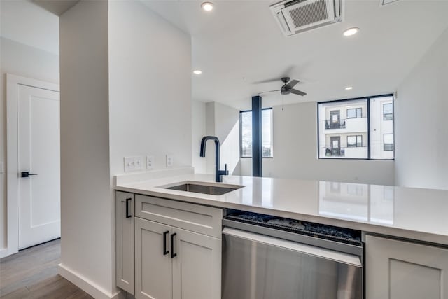 kitchen featuring ceiling fan, sink, kitchen peninsula, dishwasher, and light hardwood / wood-style floors