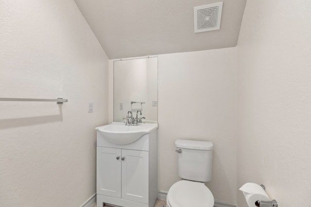 bathroom with lofted ceiling, vanity, and toilet