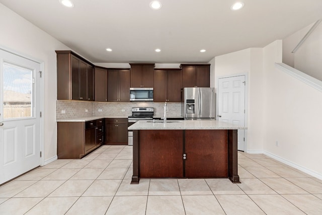 kitchen featuring appliances with stainless steel finishes, a kitchen island with sink, dark brown cabinets, and light tile patterned floors