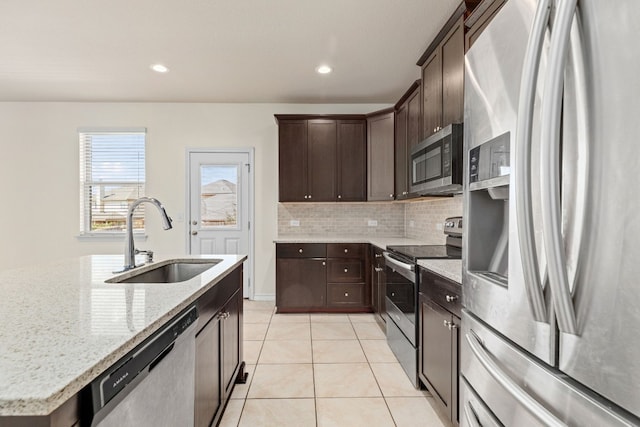 kitchen featuring light stone counters, an island with sink, light tile patterned flooring, sink, and stainless steel appliances