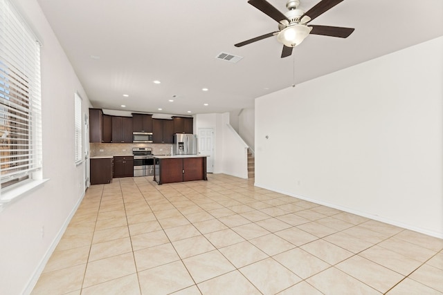 kitchen featuring ceiling fan, tasteful backsplash, stainless steel appliances, a kitchen breakfast bar, and a center island