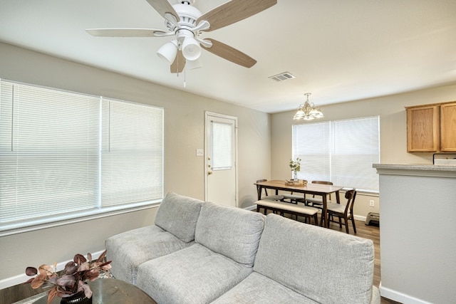 living room featuring ceiling fan with notable chandelier and hardwood / wood-style flooring