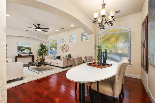 dining area with ceiling fan with notable chandelier and dark hardwood / wood-style flooring