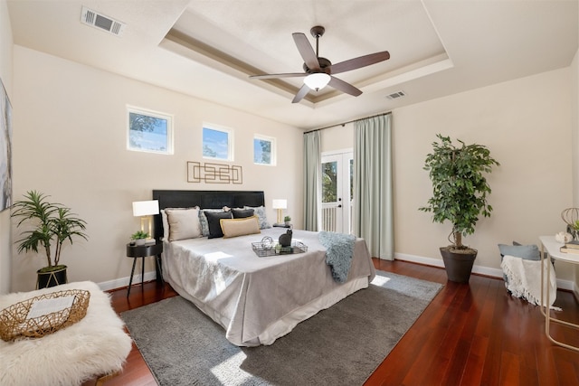 bedroom featuring a raised ceiling, ceiling fan, and dark hardwood / wood-style flooring