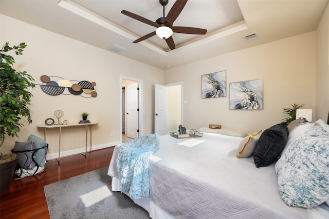 bedroom featuring ceiling fan, a raised ceiling, and dark wood-type flooring