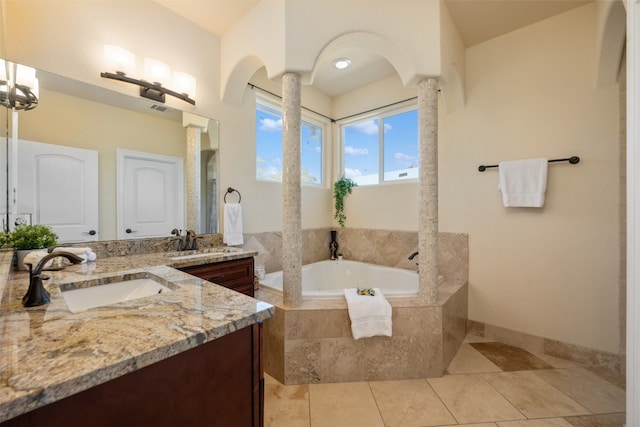 bathroom with tile patterned floors, vanity, and a relaxing tiled tub