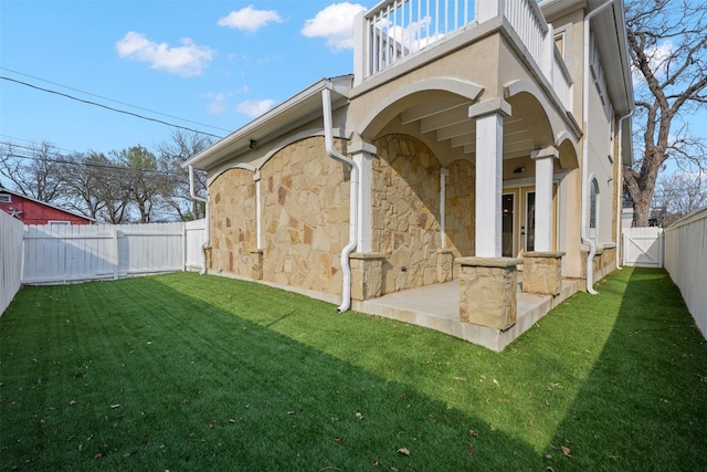 back of property with a balcony, a yard, and french doors