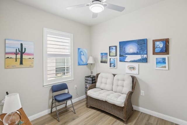 sitting room with wood finished floors, a ceiling fan, and baseboards