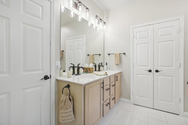 full bathroom featuring double vanity, baseboards, a sink, and tile patterned floors