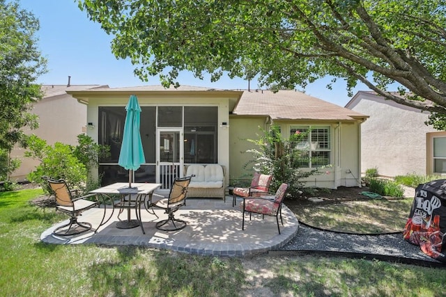 back of property featuring a yard, a sunroom, a patio, and stucco siding