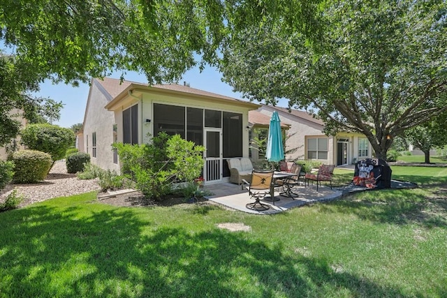 back of property with a yard, stucco siding, a sunroom, and a patio