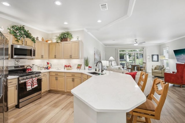 kitchen with stainless steel appliances, visible vents, light brown cabinetry, a sink, and a peninsula