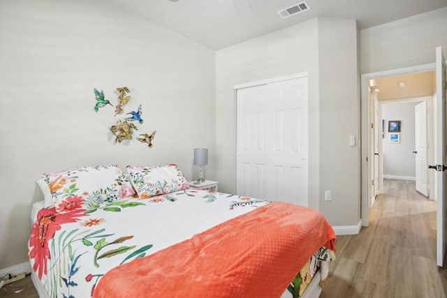 bedroom with a closet, visible vents, ceiling fan, wood finished floors, and baseboards