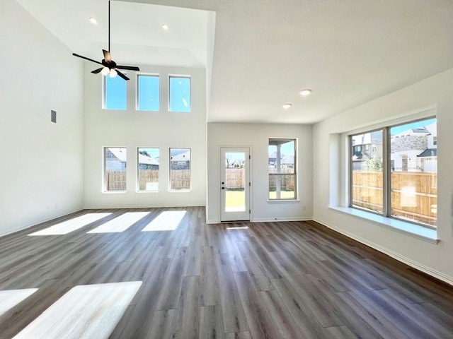 unfurnished living room with ceiling fan, dark wood-type flooring, and a high ceiling