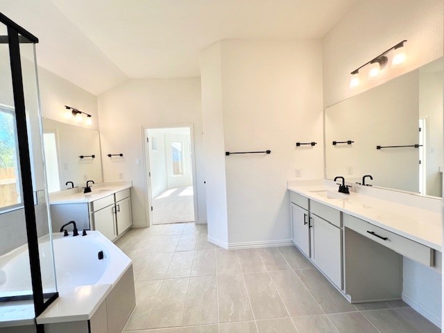 bathroom with tile patterned flooring, vanity, a tub to relax in, and lofted ceiling