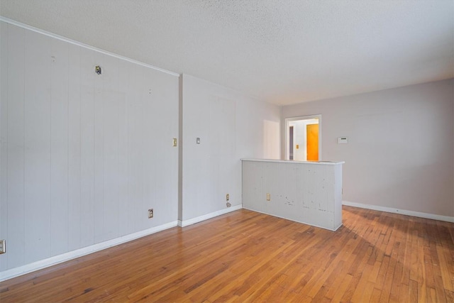 spare room featuring wood walls, a textured ceiling, and hardwood / wood-style flooring