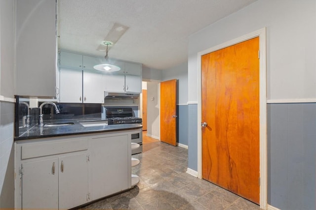 kitchen with a textured ceiling, white cabinetry, stainless steel gas range oven, and sink