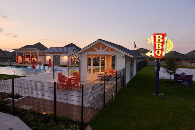 back house at dusk with a patio, a community pool, a gazebo, a yard, and a pergola