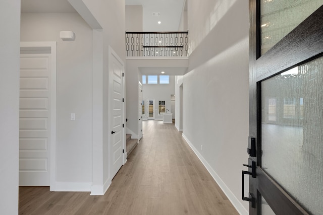 hall featuring a towering ceiling and wood-type flooring