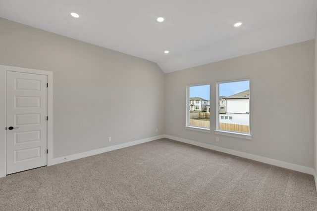 carpeted empty room with lofted ceiling