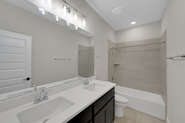 full bathroom featuring toilet, tiled shower / bath, hardwood / wood-style floors, and vanity