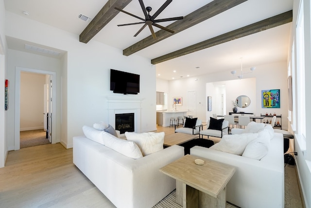 living room with light hardwood / wood-style flooring, beam ceiling, and ceiling fan