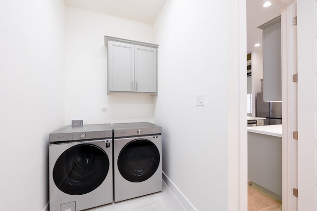 laundry area with cabinets, light tile patterned flooring, and washer and clothes dryer